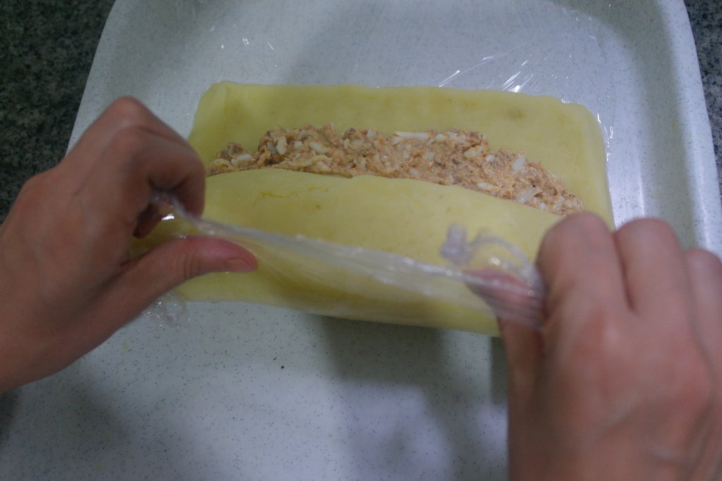 提起保鲜膜边缘开始卷制（如图示）